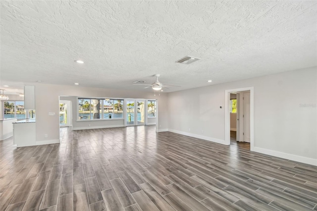 unfurnished living room featuring dark wood-style floors, baseboards, visible vents, and a ceiling fan