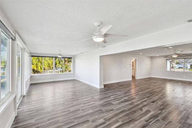 unfurnished room with ceiling fan, a textured ceiling, wood finished floors, and baseboards