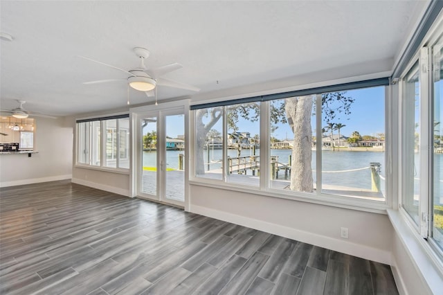 unfurnished sunroom featuring a water view and a ceiling fan