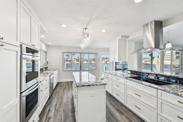 kitchen with appliances with stainless steel finishes, wood finish floors, white cabinets, and island range hood