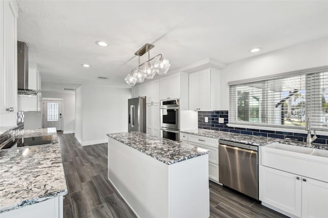 kitchen featuring appliances with stainless steel finishes, backsplash, white cabinetry, and a center island