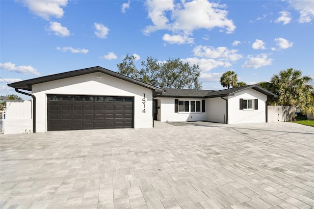 ranch-style home with an attached garage, driveway, fence, and stucco siding