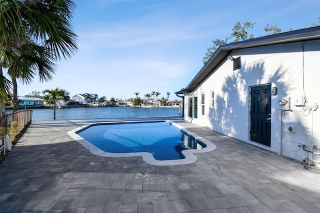 pool featuring a patio, a water view, and fence