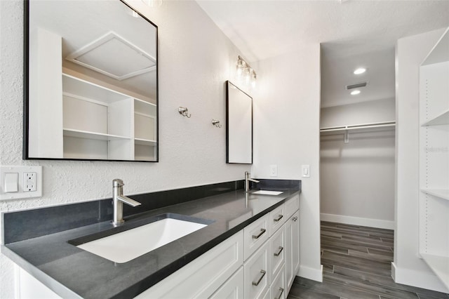 bathroom featuring a spacious closet, a sink, visible vents, and wood tiled floor