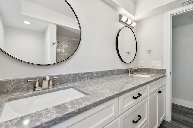 bathroom with double vanity, baseboards, visible vents, and a sink