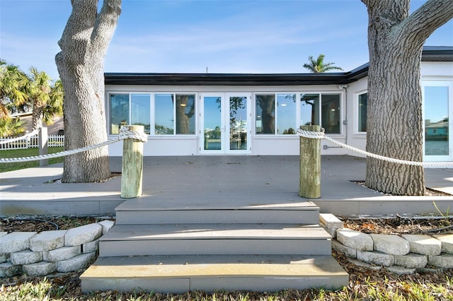 property entrance with stucco siding, fence, and a wooden deck