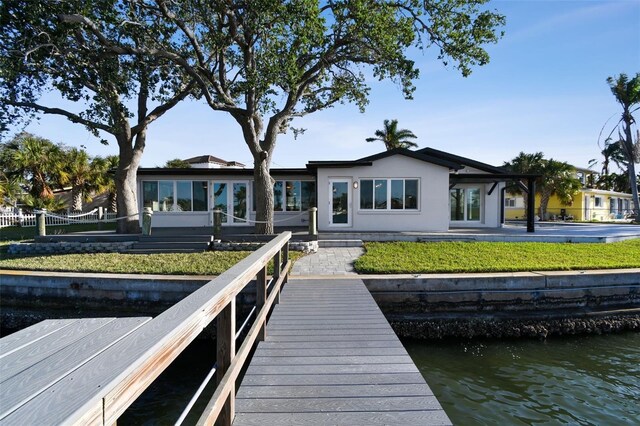 rear view of house with a water view, fence, and stucco siding