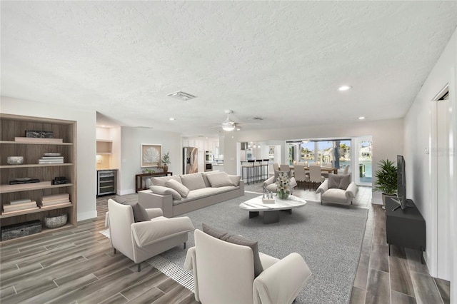 living area featuring recessed lighting, wine cooler, a textured ceiling, and wood finish floors