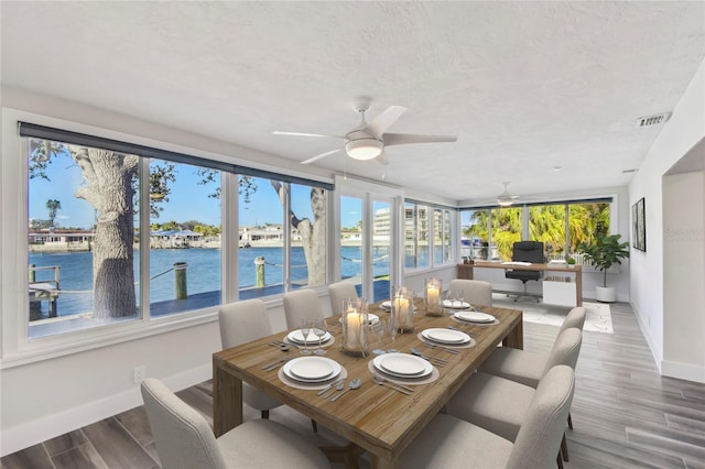 sunroom / solarium with visible vents, ceiling fan, and a water view