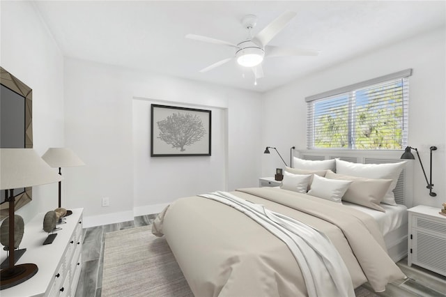 bedroom featuring ceiling fan, baseboards, and wood finished floors