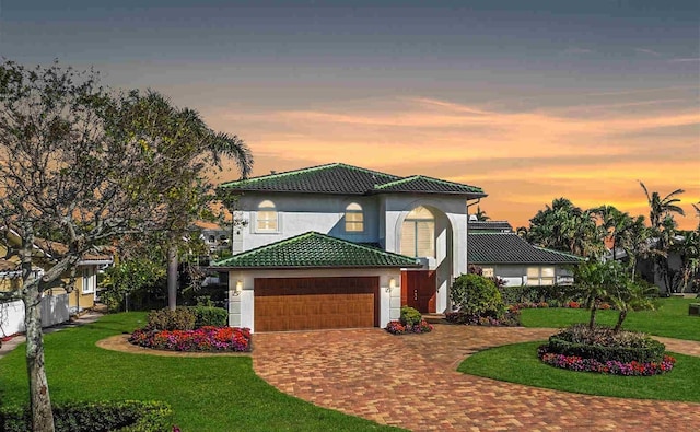 mediterranean / spanish house with a garage and a lawn