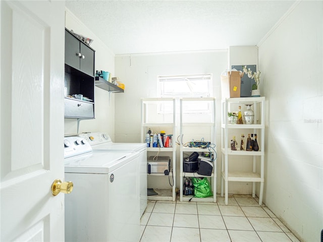 clothes washing area featuring light tile patterned flooring, washer and dryer, a textured ceiling, and ornamental molding