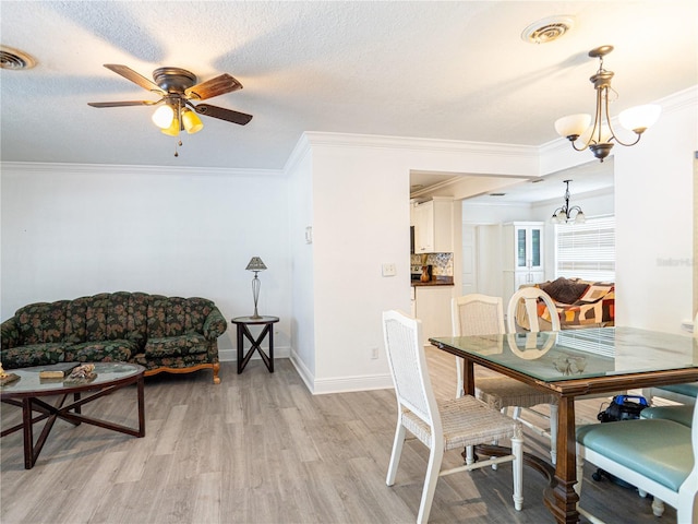 dining space featuring ceiling fan with notable chandelier, light hardwood / wood-style floors, crown molding, and a textured ceiling