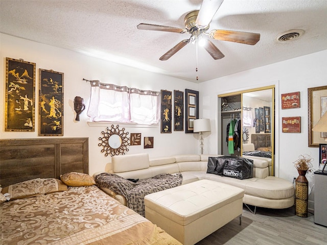 living room featuring a textured ceiling, hardwood / wood-style floors, and ceiling fan