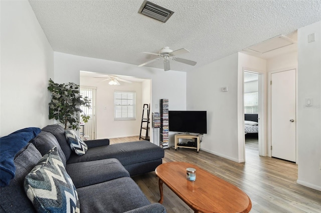 living room with ceiling fan, light hardwood / wood-style floors, and a textured ceiling