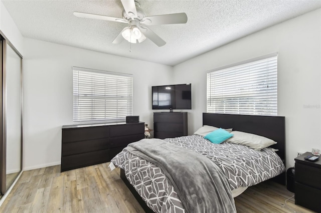 bedroom featuring ceiling fan, a closet, light hardwood / wood-style flooring, and a textured ceiling