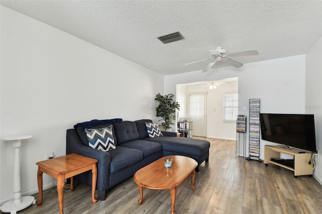 living room featuring ceiling fan, wood-type flooring, and a textured ceiling