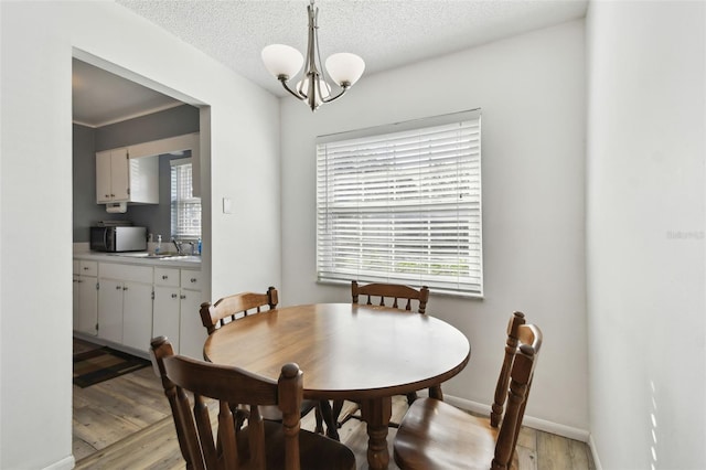 dining area with a notable chandelier, plenty of natural light, a textured ceiling, and light wood-type flooring