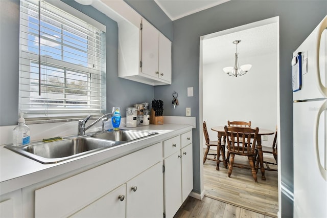 kitchen with sink, light hardwood / wood-style flooring, white cabinetry, white refrigerator, and decorative light fixtures