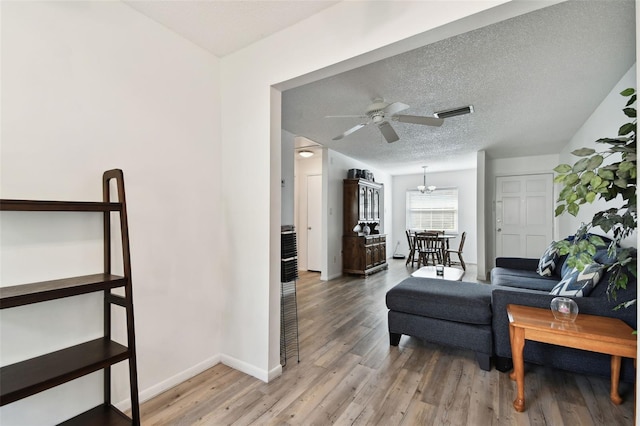 interior space featuring hardwood / wood-style flooring, ceiling fan with notable chandelier, and a textured ceiling