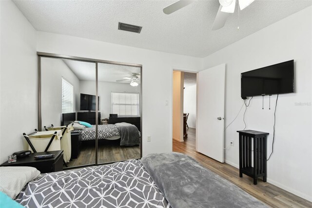 bedroom with a closet, ceiling fan, hardwood / wood-style floors, and a textured ceiling