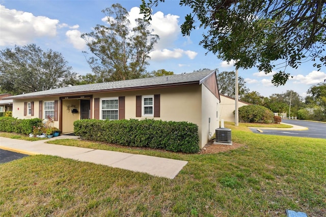 ranch-style home with central AC unit and a front lawn