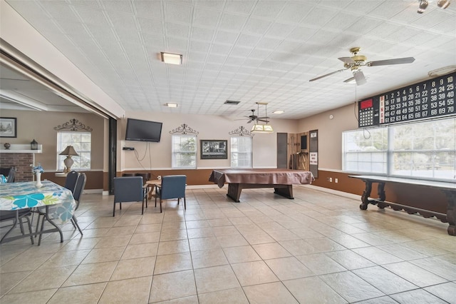 game room featuring light tile patterned floors, ceiling fan, and a brick fireplace