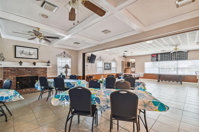 dining room featuring light tile patterned flooring, a fireplace, coffered ceiling, and beamed ceiling