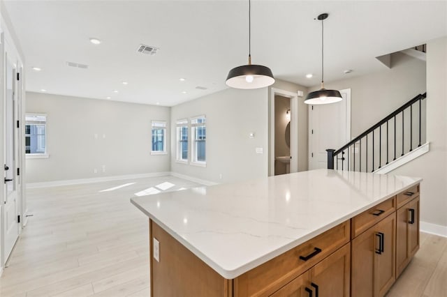 kitchen featuring a kitchen island, visible vents, brown cabinets, and decorative light fixtures