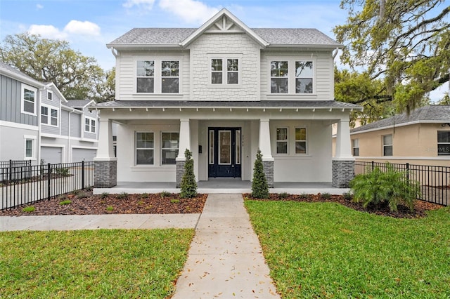 view of front of house with a porch, a front lawn, a shingled roof, and fence