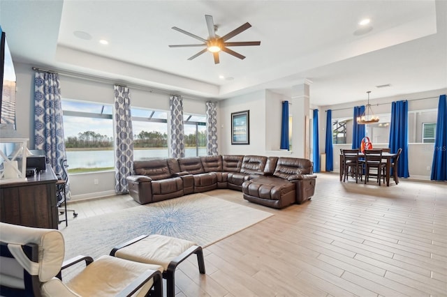 living room with a water view, light hardwood / wood-style flooring, and a tray ceiling