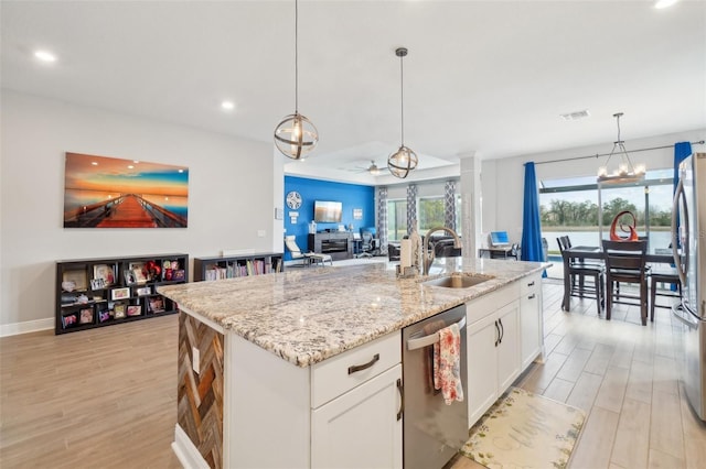 kitchen with sink, appliances with stainless steel finishes, hanging light fixtures, an island with sink, and white cabinets