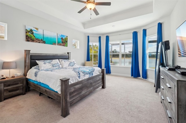 carpeted bedroom featuring a raised ceiling and ceiling fan