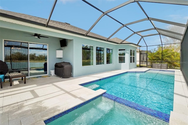 view of swimming pool with ceiling fan, a patio area, and glass enclosure