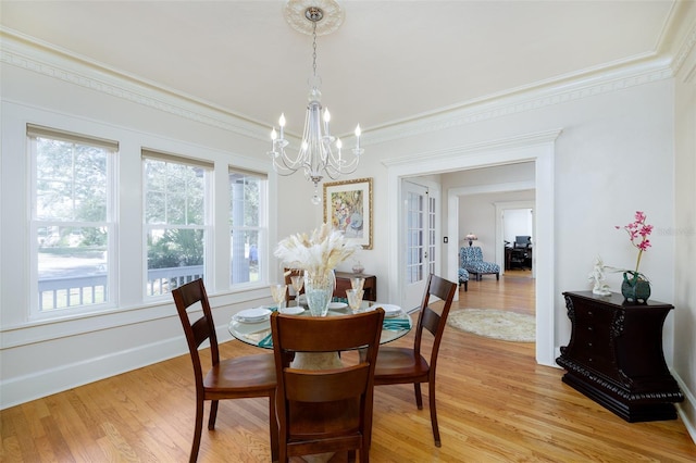 dining area featuring crown molding, light hardwood / wood-style floors, and a chandelier