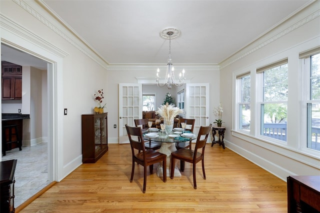 dining area featuring crown molding, light hardwood / wood-style flooring, and a notable chandelier