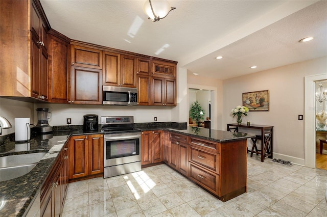 kitchen with sink, a textured ceiling, appliances with stainless steel finishes, kitchen peninsula, and dark stone counters