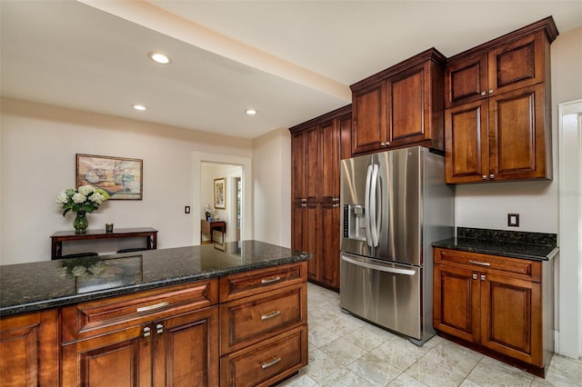 kitchen featuring dark stone counters and stainless steel fridge