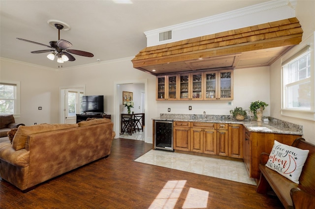 interior space featuring crown molding, light stone countertops, wine cooler, and light hardwood / wood-style flooring