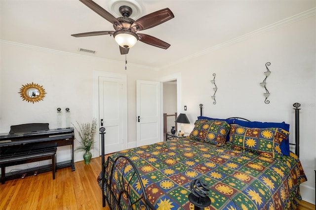 bedroom with hardwood / wood-style floors, ornamental molding, and ceiling fan