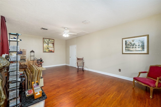 sitting room with ceiling fan, dark hardwood / wood-style flooring, and a textured ceiling