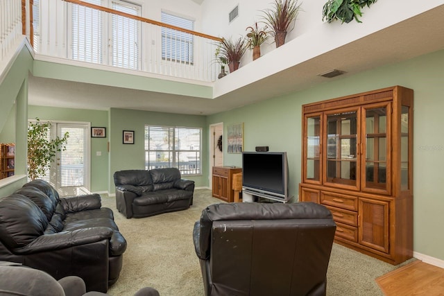 carpeted living room with a wealth of natural light and a high ceiling