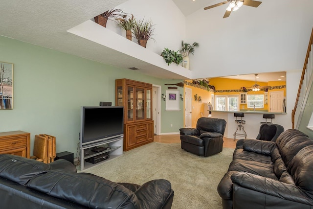 living room featuring carpet floors, sink, ceiling fan, and a towering ceiling