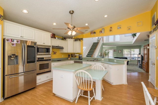 kitchen with white cabinetry, stainless steel appliances, a kitchen bar, and kitchen peninsula