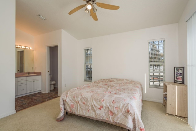 carpeted bedroom with ceiling fan, ensuite bathroom, and sink