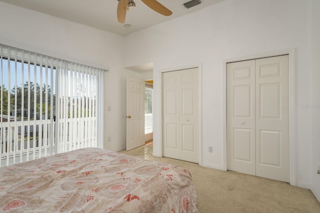 carpeted bedroom featuring ceiling fan and multiple closets