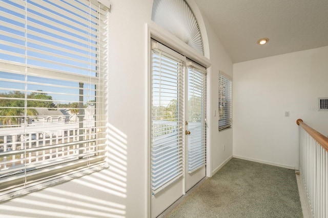 hallway with light carpet and a textured ceiling