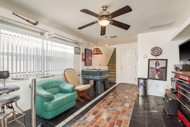 living room with ceiling fan and a textured ceiling