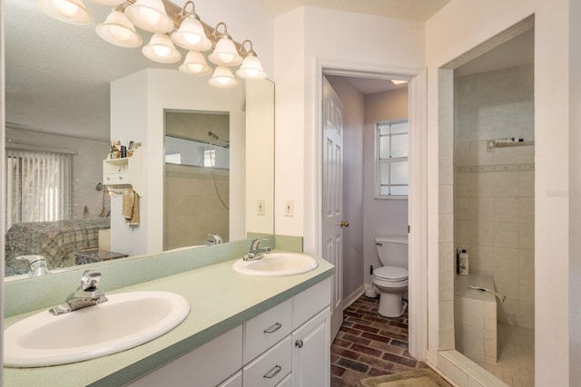 bathroom featuring vanity, a textured ceiling, toilet, and a tile shower