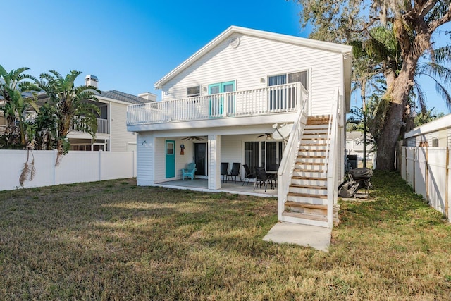 back of property with ceiling fan, a yard, and a patio